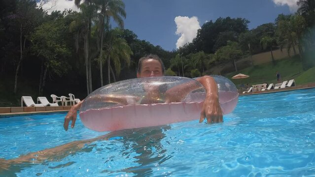 Young woman in pool floaty turning around on hot summer day - close up