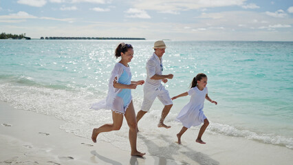 Family Running Together On Beach