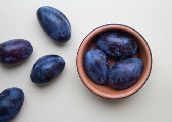 Fresh ripe of plums in brown bowl. Top view. Neutral background
