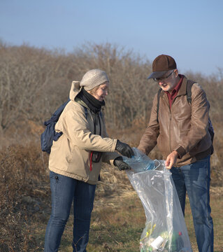 Senior man and woman collecting plastic trash while on a hiking trip
