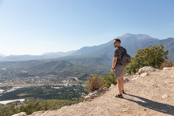 The man on a mountaintop admiring the surrounding mountain landscape