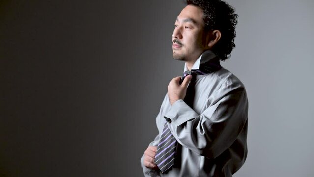 ダンディな髭の男性がネクタイをしめるところ