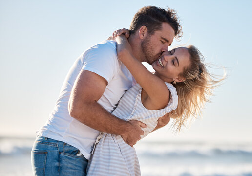 Love, dating and couple kiss at beach enjoying summer holiday, vacation and honeymoon by the sea. Travel, romance and man and woman show affection, embrace and bonding in nature on weekend together