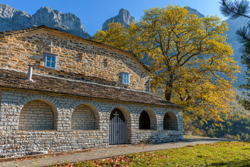 Fototapeta premium Taxiarchon stone built church during fall season in the picturesque village of Mikro papigo in Epirus zagori greece