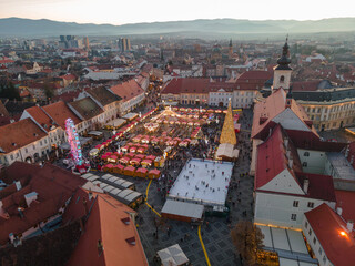 Landscape photography of Sibiu city center with the Christmas Fair, shot from a drone at sunset with the city lightning on. Birds eye view over cityscape of Sibiu, Romania.