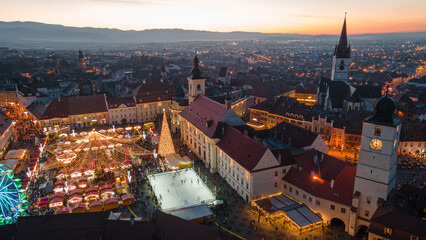 Fototapeta na wymiar Landscape photography of Sibiu city center with the Christmas Fair, shot from a drone at sunset with the city lightning on. Birds eye view over cityscape of Sibiu, Romania.