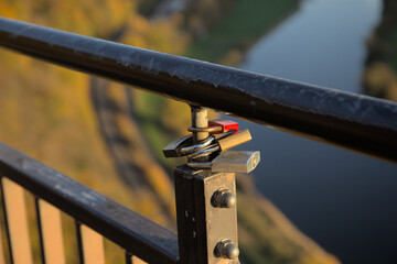 Love locks on a railing on a viewing platform in a rural setting over a valley with a river