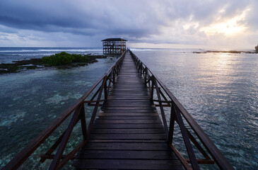 Obraz premium Beautiful landscape. Sunset on the seashore. Wooden bridge on Cloud Nine beach, Siargao Island Philippines.