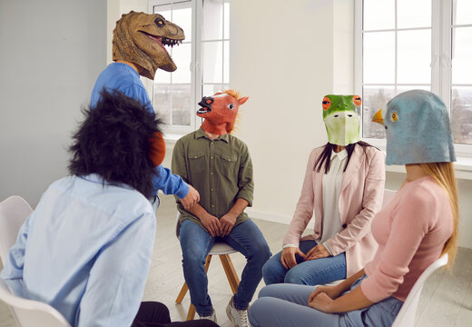 People wearing strange animal masks talking during a group therapy session. Male and female patients with funny animal faces sitting in a circle and listening to each other at a group therapy meeting