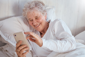 Happy elderly woman, bed or phone on social media for meme, comic or joke on internet. Senior lady, bedroom or smartphone tech with laugh at social network, funny video or email on web, app or online