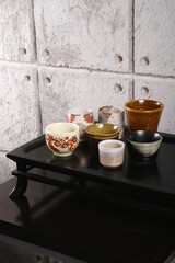 Collection of clay and ceramic cups and bowls on a black surface