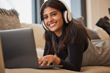 Headphone, woman and relax on laptop, happy and listening to music, podcast or watch a movie on the sofa in home. Portrait, young girl and happy with streaming subscription app, audio or social media