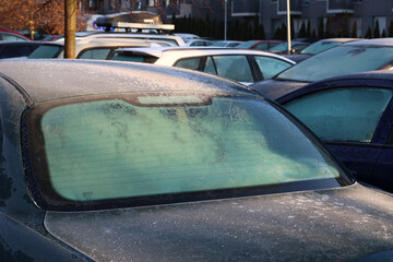 Oszronione szyby samochodów w zimowy poranek na parkingu. 