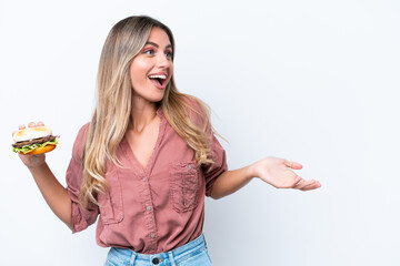 Obraz premium Young pretty Uruguayan woman holding a burger isolated on white background with surprise facial expression