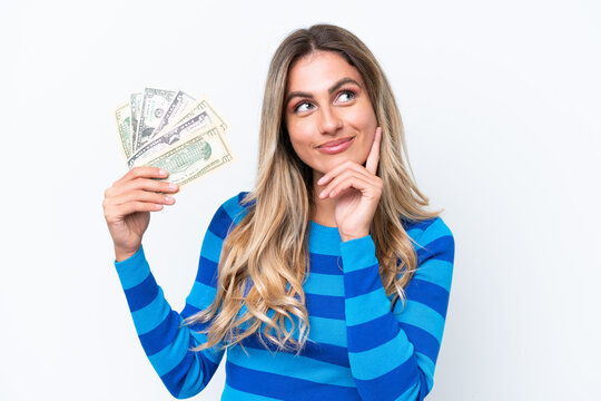 Young Uruguayan woman taking a lot of money isolated on white background thinking an idea while looking up