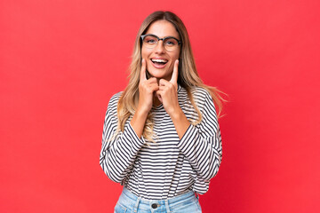 Young Uruguayan woman isolated on red background smiling with a happy and pleasant expression