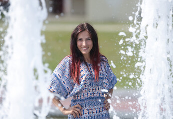 A beautiful young woman poses against the background of a fountain