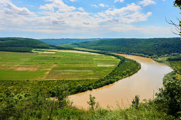 Fototapeta na wymiar Summer river flowing among green hills and fields. Tovtry National Park Ukraine