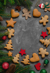 Christmas frame with traditional gingerbread cookies, fir branches and Christmas decoration on a grey background. Copy space. Cookies, baubles, stars, fir tree branches.