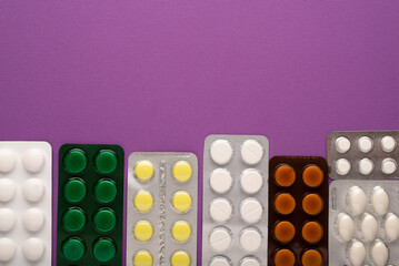 Pills in blister packs on a lilac background with space for text. Medicines oncology, colds, covid.