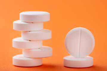 Round white pills close-up on an orange background. Antibiotics and vitamins from all diseases super macro.