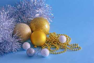 Christmas decorations. Yellow and white Christmas balls and silver tinsel on blue background. Copy...