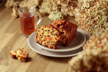  Fruit cake and tea on a wooden table with dried flowers.