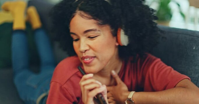 Phone, music and dance with a black woman singing while having fun in the living room of her home. Smartphone, karaoke and singer with a young female streaming or listening to audio on the sofa