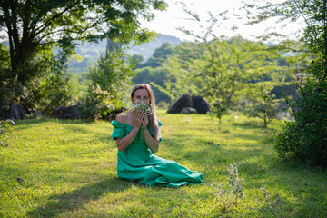 a woman is sitting on the grass with flowers in a green dress