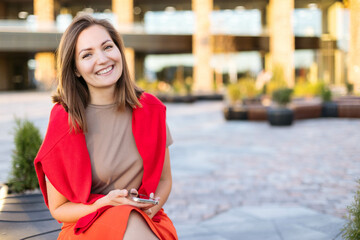 Close-up portrait of a young woman laughing happily, outdoors against the backdrop of city buildings