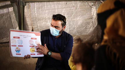 a doctor explains to refugees how to prevent a cholera epidemic