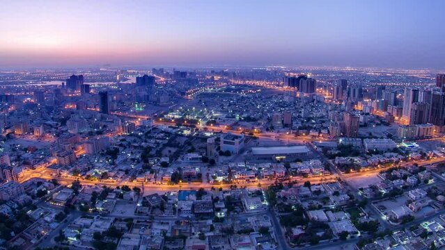 Panoramic cityscape of Ajman from rooftop from night to day transition timelapse before sunrise. Ajman is the capital of the emirate of Ajman in the United Arab Emirates.