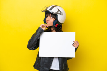 Young latin woman with a motorcycle helmet isolated on yellow background holding an empty placard and thinking