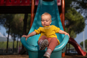 Fototapeta na wymiar Cute little girl having fun on outdoor playground. Child on plastic slide. 