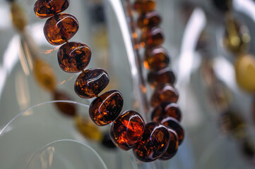 Dark amber beads on a glass shelf.