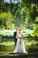 Fototapeta na wymiar Young beautiful couple in a blue suit and white wedding dress with a bouquet in the hotel