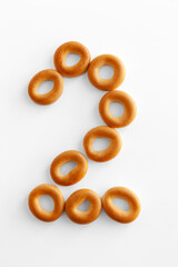 Bagels font. Alphabet from set of small dry bagels isolated on white background. ABC symbols.  Number 2.