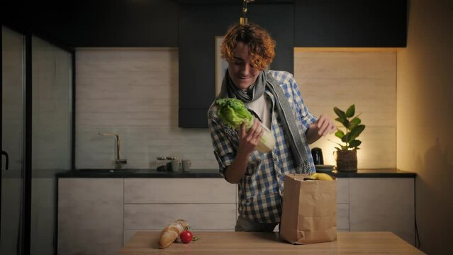  Young Man Brings Groceries to the Kitchen.Attractive guy unpacking shopping bag in home interior.Online Food Delivery Concept.