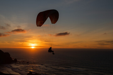 Paraglider flying over thesea shore at sunset. Paragliding sport concept.