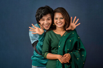 Portrait of a happy cheerful young couple posing on dark background. Attractive man and woman being playful.