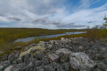 In autumn, the tundra with a lake and large stones.