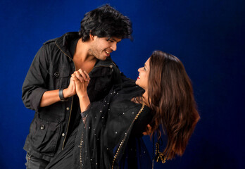 Portrait of a happy cheerful young couple posing on dark background. Attractive man and woman being playful.