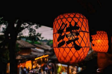 Closeup shot of an  lighted Chinese red lantern with hieroglyphs sign on it outdoors