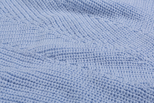 The texture of a light blue knitted woolen fabric, close-up, fabric with folds