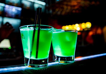 Glass of green cocktail on bar background