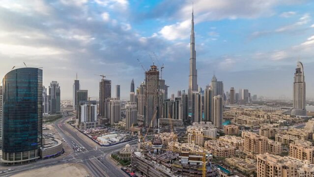Beautiful luxury Dubai downtown aerial top view during all day timelapse, Dubai, United Arab Emirates. Rooftop view from business bay towers with clouds on blue sky. Traffic on the road