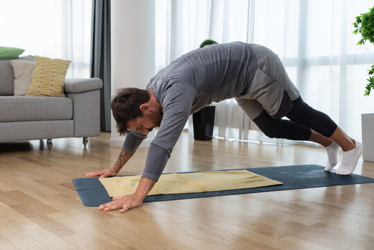 Young handsome fit man start to thing about himself after relationship breakup or marriage divorce and exercising at his home to improve his life. Home workout motivation and self love concept