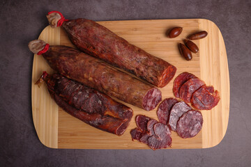 Iberico sausage, Iberico chorizo and Iberico loin on cutting board and dark gray table, garnished with acorns - obrazy, fototapety, plakaty