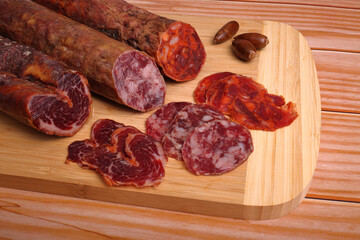 Iberian sausage, Iberian chorizo and Iberian loin on cutting board and wooden table, garnished with acorns - obrazy, fototapety, plakaty