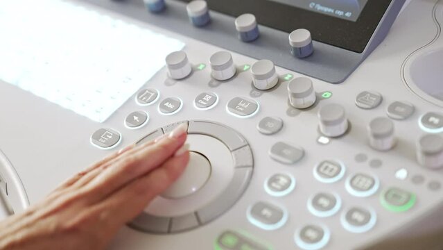 Physician’s hand pressing the buttons on the keyboard of ultrasound machine. Close up. Advanced equipment for ultrasonic diagnostics in clinics.